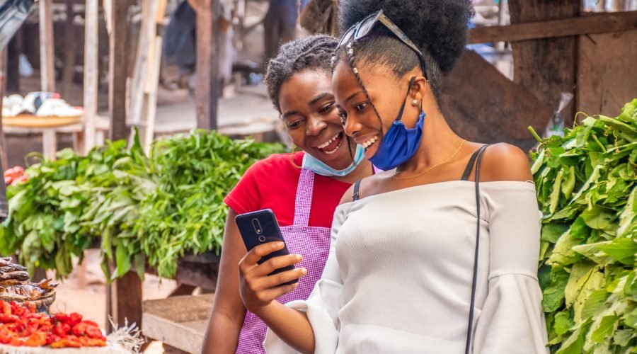 The two women viewing content on a phone in a local African market.