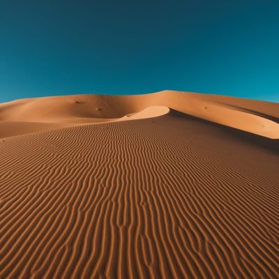 A vertical shot of a peaceful desert under the clear blue sky captured in Morocco